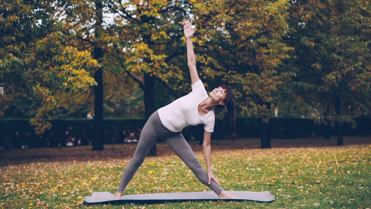 Mastering the First Impression: Your intriguing post title goes here A woman performs yoga on a mat in a scenic park with colorful autumn trees.
